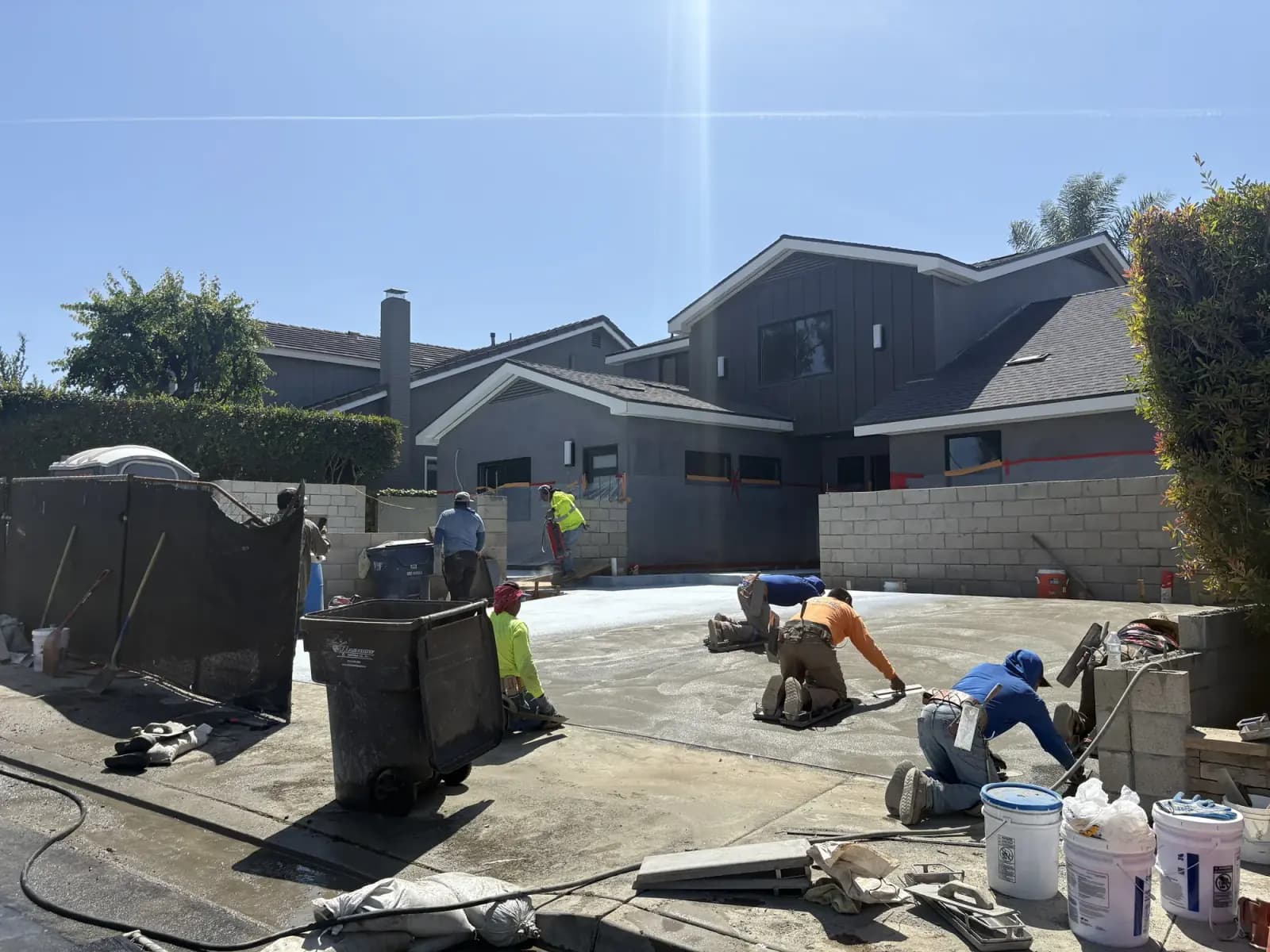 A crew finishing a concrete pour between new block walls, buggies and floats in use