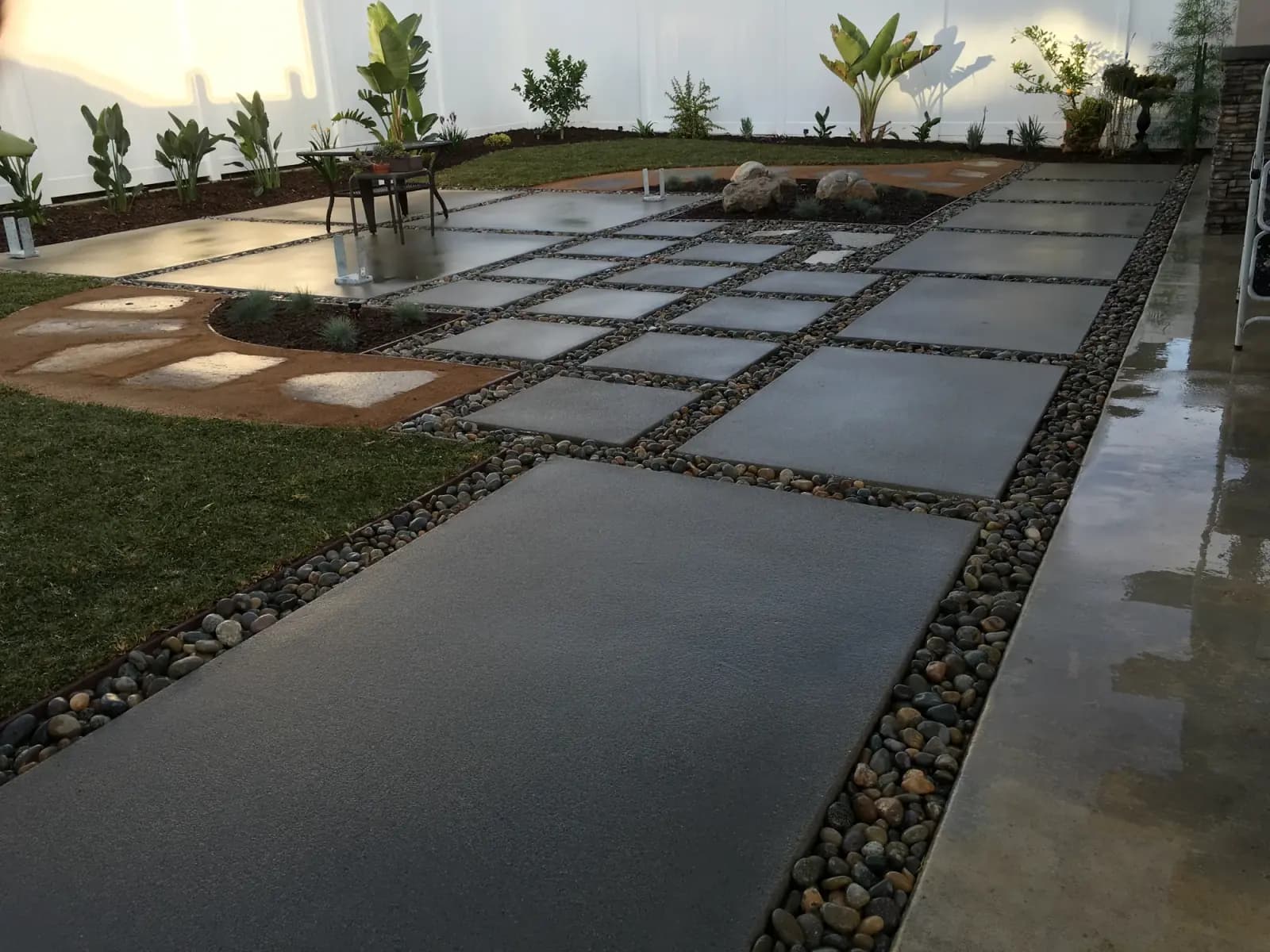 A finished path of large concrete pavers set in gravel joints, new planting either side