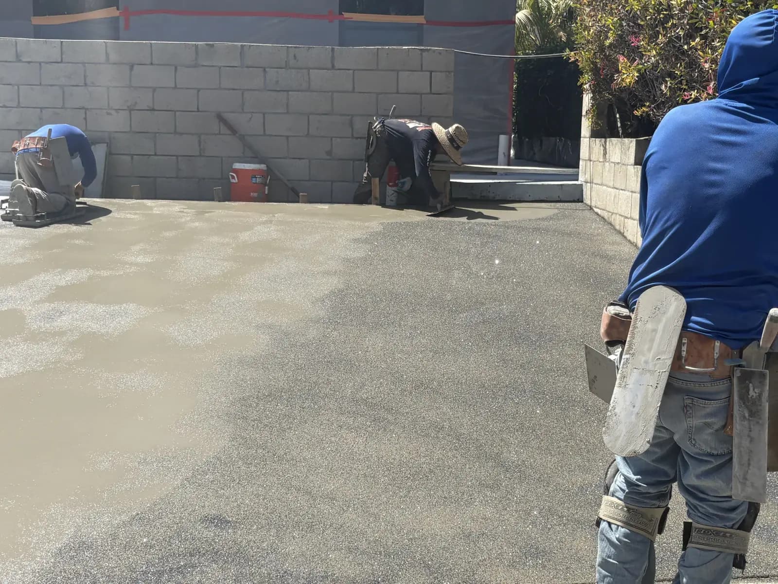 A freshly poured concrete slab being floated smooth, block walls to either side